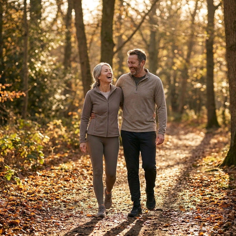 Couple walking together on a sunlit autumn woodland path
